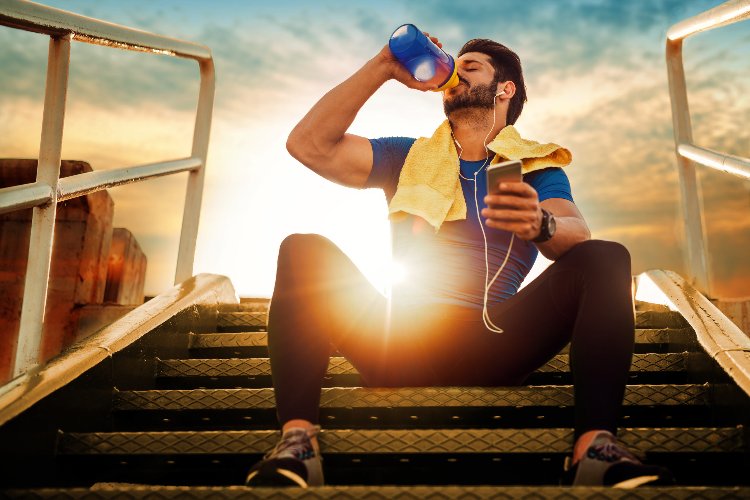 man drinking water recovering after workout